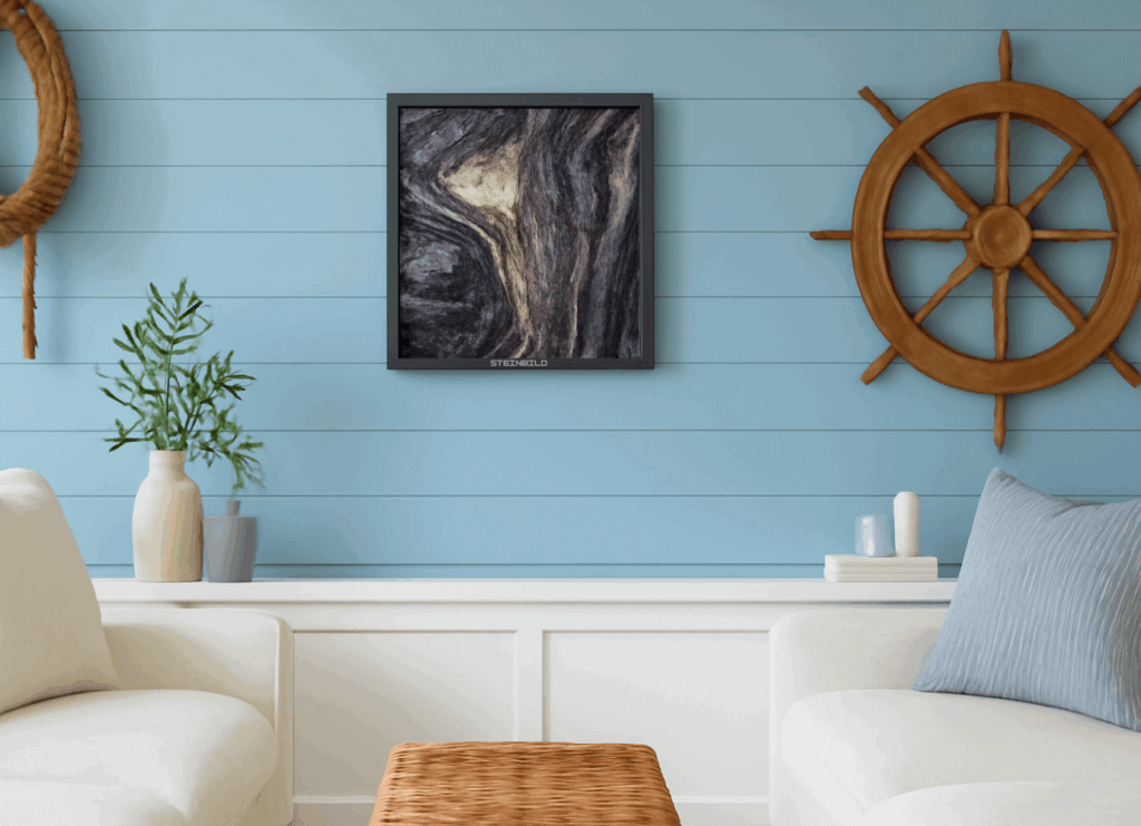 Wohnbereich im maritimen Stil mit einer Wanddekoration aus Schiffsrädern, einem schwarz gerahmten abstrakten Steindruck, hellblau getäfelten Wänden und weißen Sesseln mit minimalistischen Accessoires.