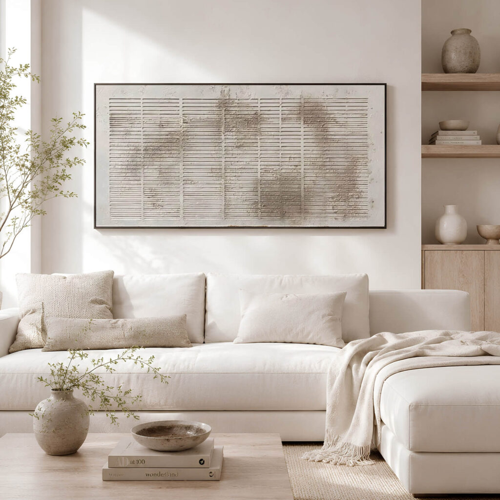 Ein großes, horizontales und strukturiertes abstraktes Gemälde an einer hellen Wand über einem weißen Sofa in einem minimalistischen Wohnzimmer im Wabi-Sabi-Stil.