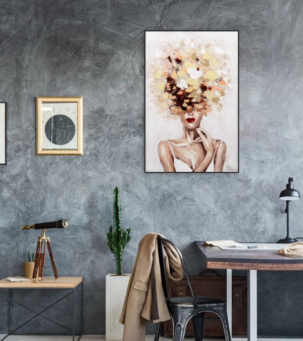 Vertical abstract oil painting of a woman with vibrant floral-textured hair in autumn tones, displayed on a textured grey concrete wall in a modern home office.