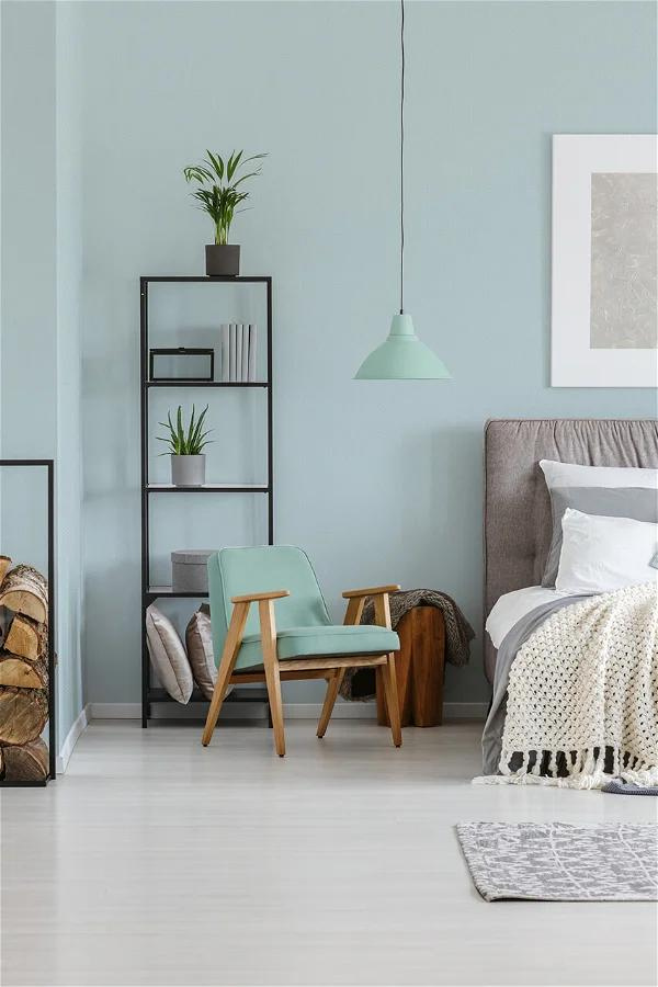 ein Schlafzimmer mit schlichter himmelblauer Tapete und Bücherregalen