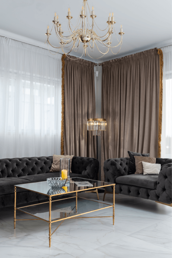 Ein modernes Wohnzimmer mit braunem Vorhang, Deckenleuchten, dunklem Sofa und Stehlampe